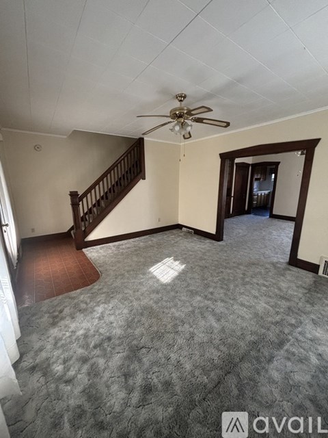 A living room with a staircase and a ceiling fan.