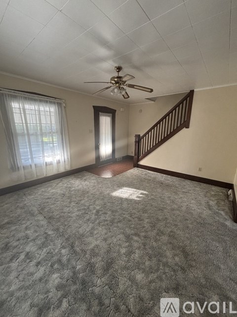 A room with a carpeted floor and a ceiling fan.