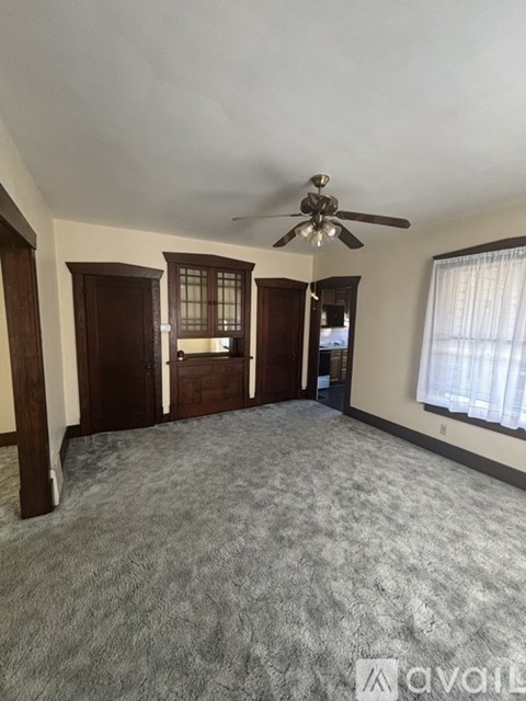 A room with a ceiling fan and carpeted floor.
