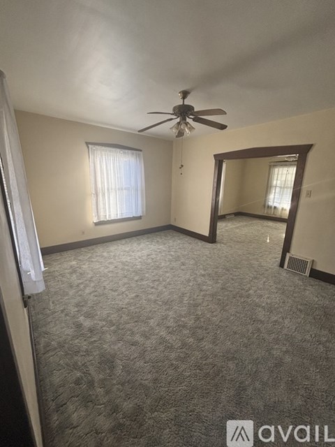A room with a carpeted floor, a ceiling fan, and a mirror.