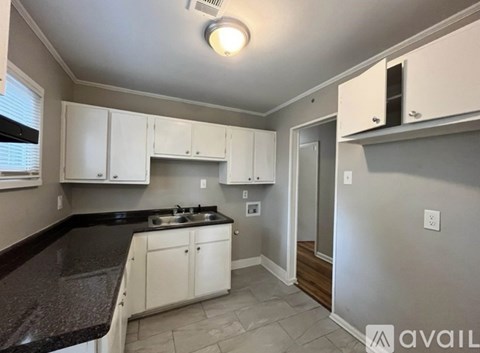 A kitchen with white cabinets and a black countertop.