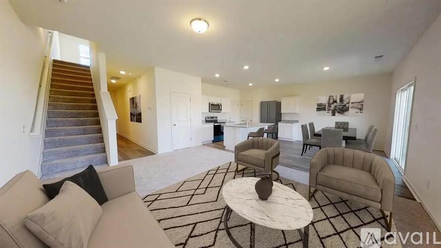 A living room with a staircase and a kitchen in the background.