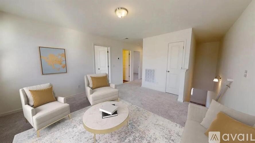 A living room with a coffee table, two chairs, and a painting on the wall.