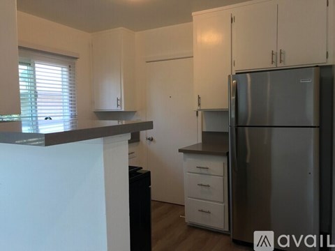 A kitchen with white cabinets and a stainless steel refrigerator.