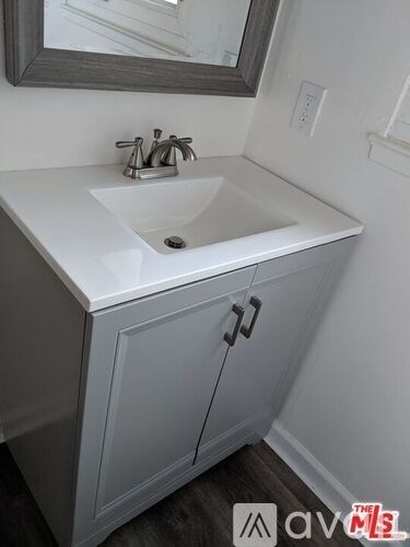 A white sink is in a cabinet with a mirror above it.