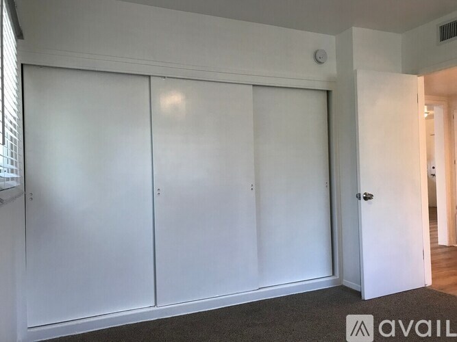 A room with white walls and a carpeted floor with three white doors.