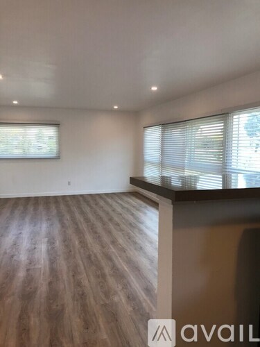 A room with wooden flooring and a window with blinds.