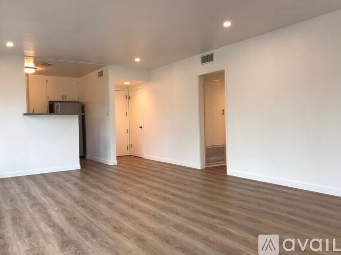 A spacious room with wooden flooring and white walls.