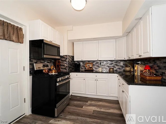 A kitchen with black appliances and white cabinets.