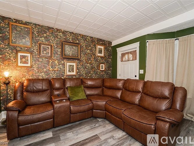 A brown leather sectional sofa with a green pillow in the middle.
