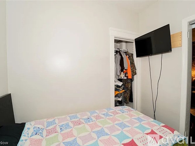 A bedroom with a bed, a wardrobe, and a TV mounted on the wall.