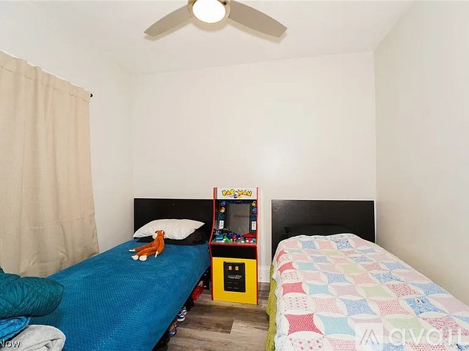 A bedroom with a blue bed and a yellow arcade machine.
