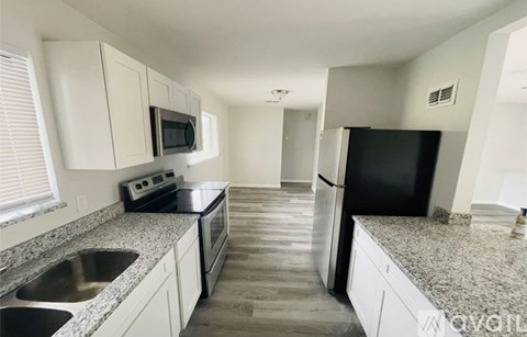 A kitchen with a black refrigerator and white cabinets.