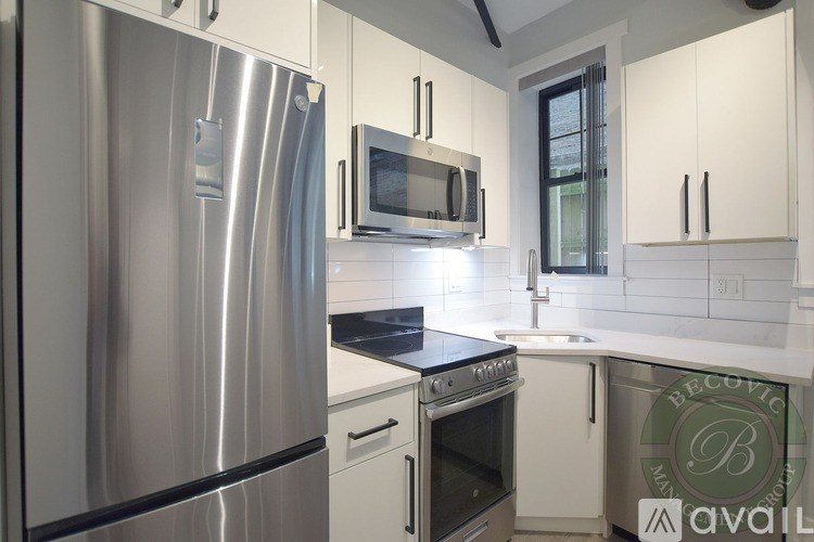 A modern kitchen with a stainless steel refrigerator and white cabinets.