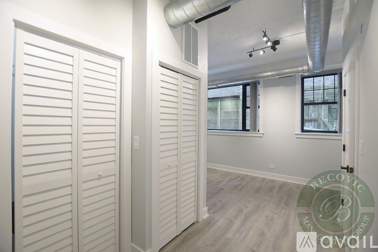 Closed white shutter doors in a room with a window.
