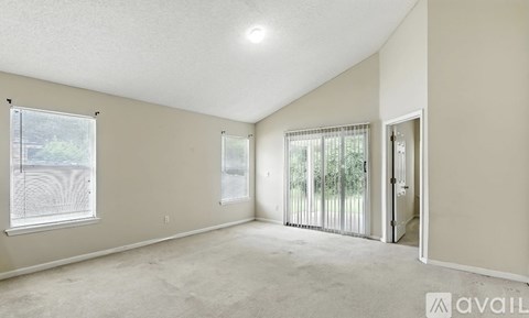 A spacious room with a sliding glass door leading to a balcony.