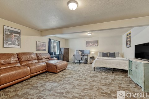 A living room with a brown leather couch and a television.