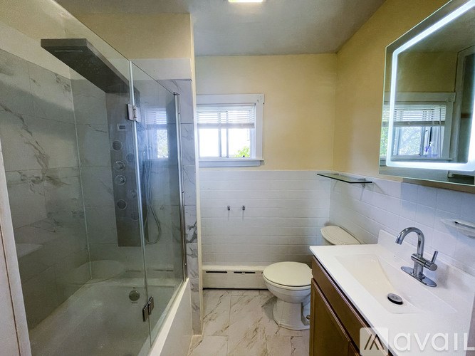 A bathroom with a glass shower stall, toilet, and sink.
