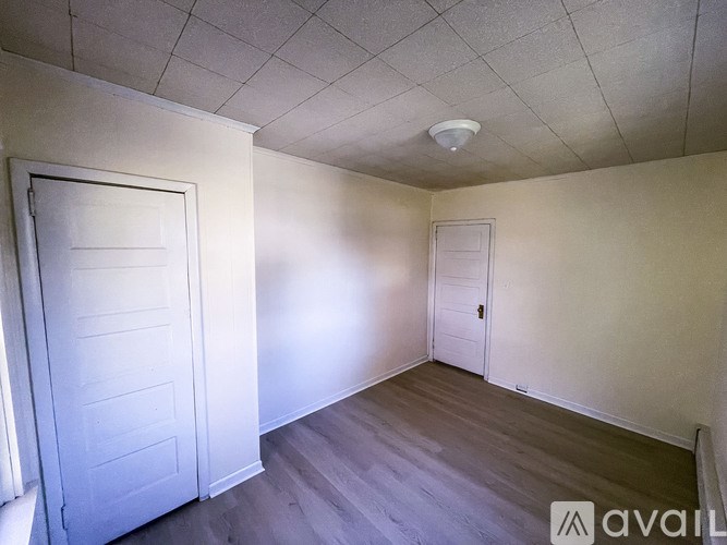 A room with a white door and a white ceiling with a smoke detector.