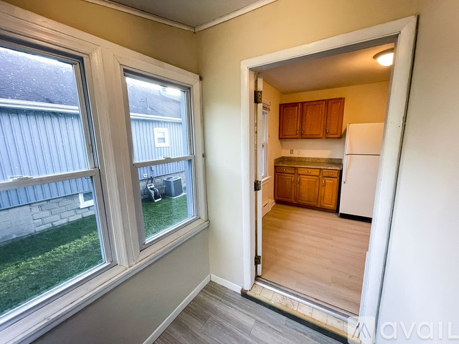 A room with a window and a door leading to a kitchen.