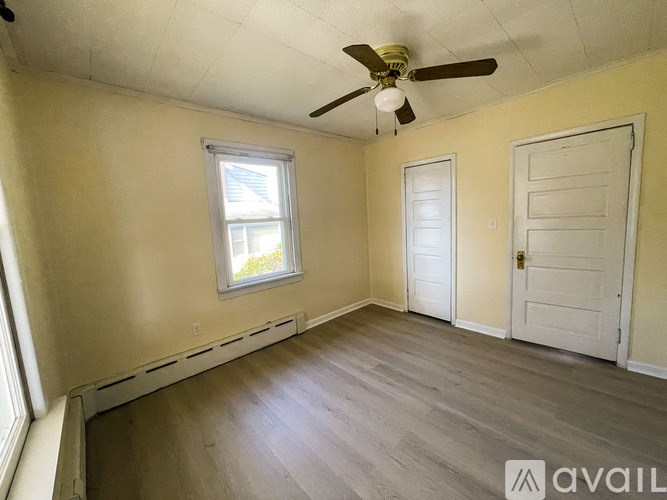 A room with a ceiling fan, two doors, and a window.
