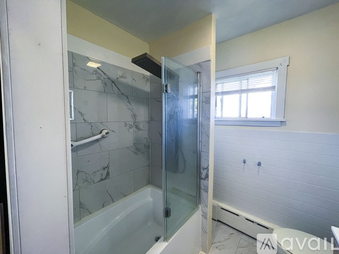 A bathroom with a marble tile shower and a glass door.