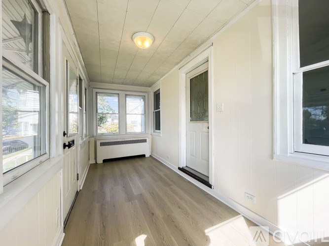 A sunny day in a long hallway with a white door.