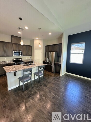 A kitchen with a granite countertop and a refrigerator in the background.