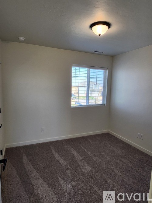 A room with a carpeted floor and a window with blinds.