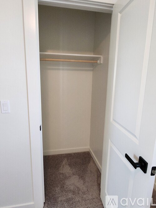 A room with carpeted floor and a window with blinds.