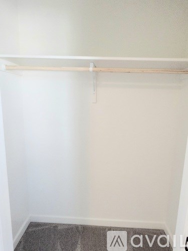 A white wall with a white shelf and a grey carpet.