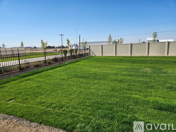 A large, well-maintained lawn with a fence and a building in the distance.