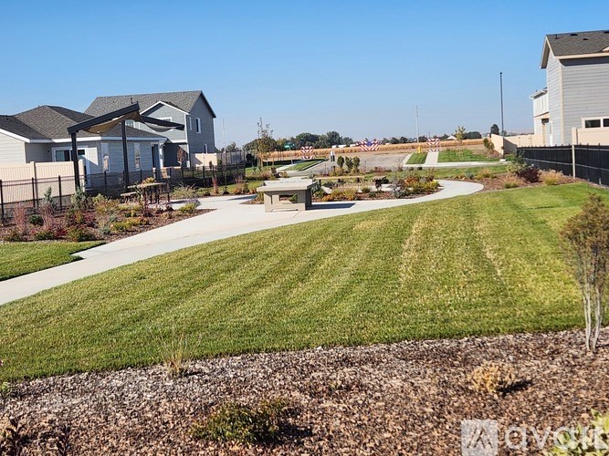 A grassy field with a few houses in the background.