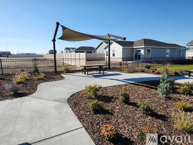 A residential area with a pathway and a bench under a shade sail.
