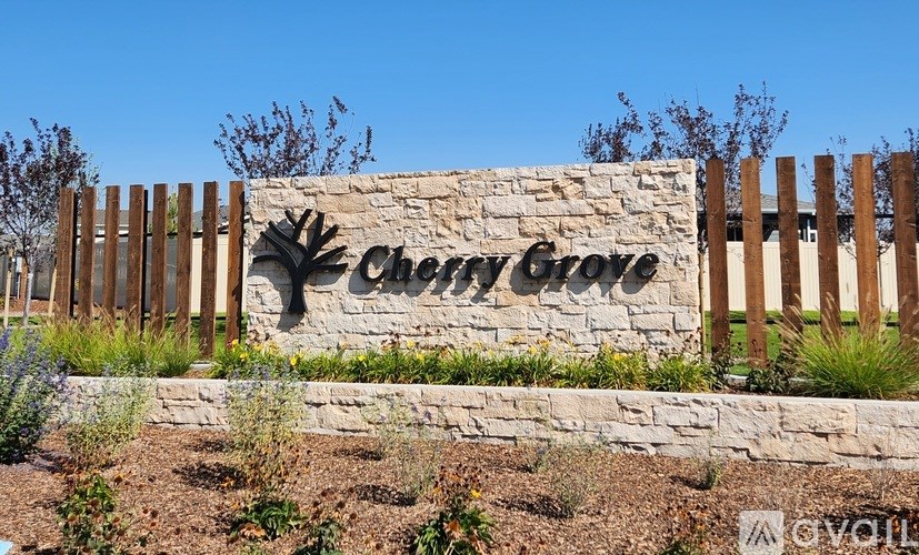 A sign that says Cherry Grove in front of a fence.