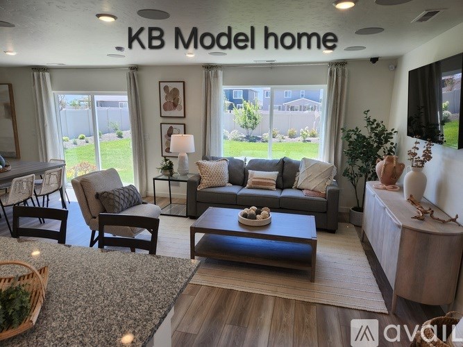 A well-lit living room with a grey sofa, a wooden coffee table, and a TV mounted on the wall.