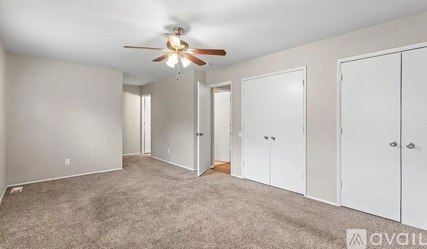 A room with a ceiling fan and carpeted floor.