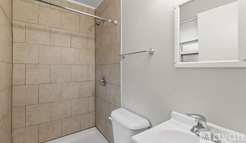 A bathroom with a toilet, sink, and tiled shower.