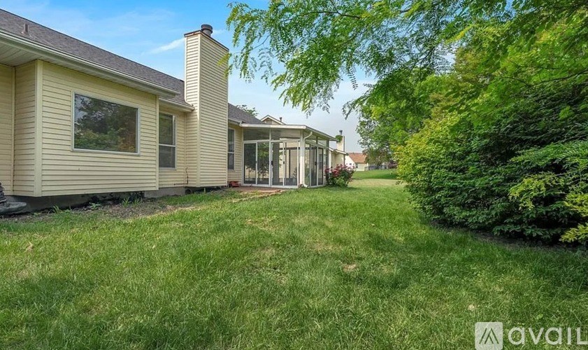 A house with a large lawn and trees in the background.