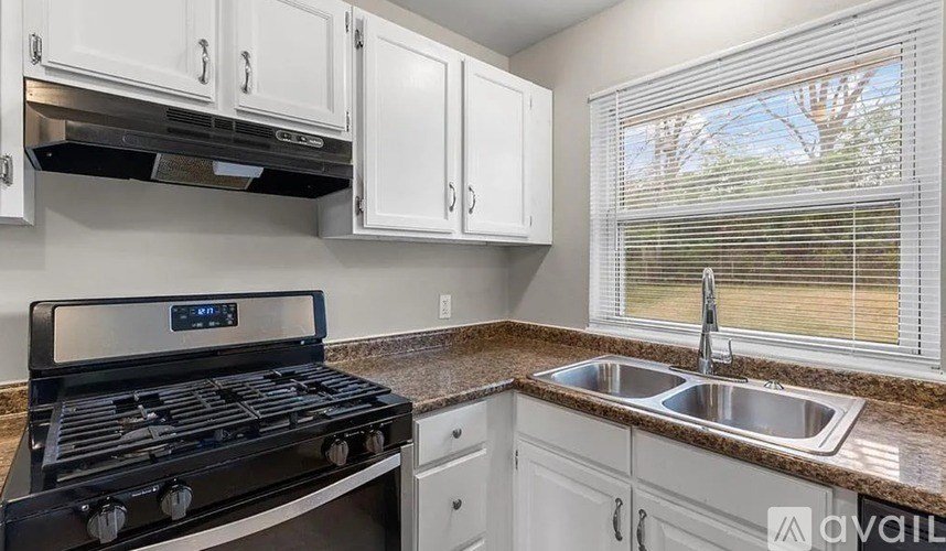 A kitchen with a black stove and white cabinets.