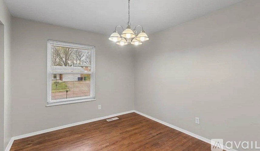A room with wooden flooring and a picture of a tree-lined street on the wall.