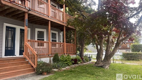 A house with a balcony and a tree in front.