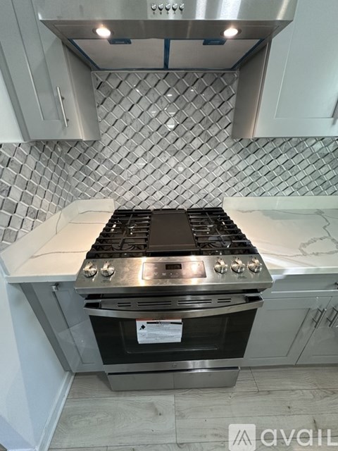 A modern kitchen with a stove top oven and a tile backsplash.