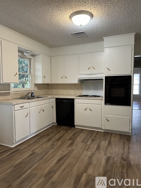 A kitchen with white cabinets and a wooden floor.