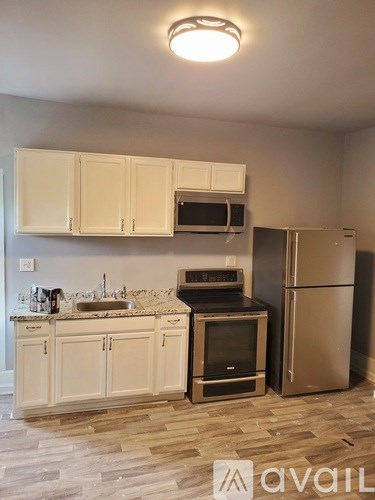 A kitchen with a refrigerator, sink, and cabinets.