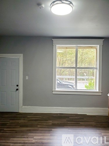 A room with a white door and a window with a view of a street.