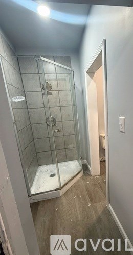 A bathroom with a glass shower stall and a wooden floor.