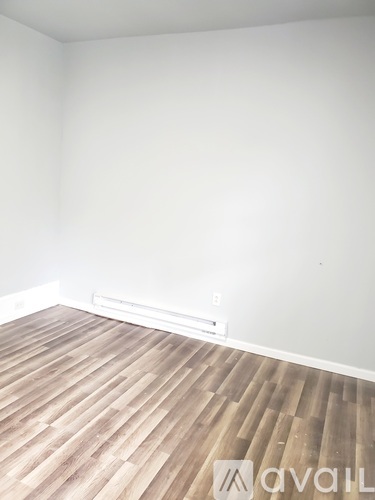 A room with wooden flooring and a white wall.