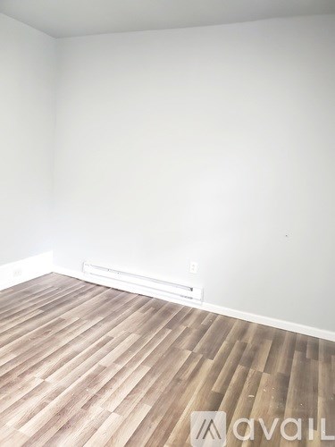 A room with wooden flooring and a white wall.