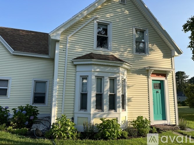 A yellow house with a green door and a sign that says "available".